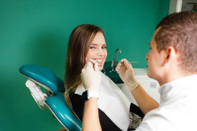 Foto dentista examina os dentes de seu paciente. garota atraente está sendo examinada por um dentista