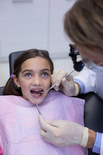 Dentista examina a un paciente joven con herramientas