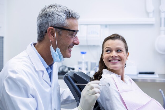 Foto dentista examina a un paciente joven con herramientas