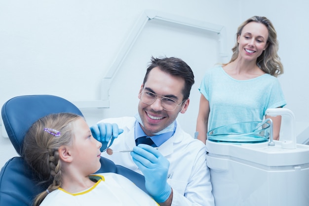 Dentista examinando as dentes das meninas com o assistente