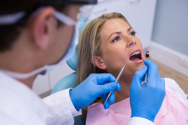 Dentista examinando boca de mulher na clínica