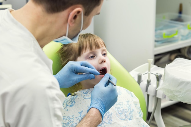 Dentista examinando los dientes de una niña en la clínica Problema dental