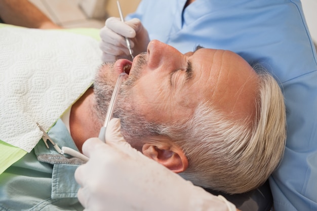 Dentista examinando los dientes de un paciente en la silla de los dentistas