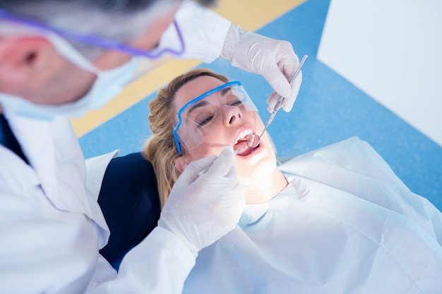Dentista examinando los dientes de un paciente en la silla de los dentistas