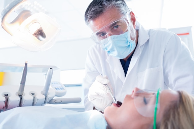 Dentista examinando los dientes de un paciente en la silla de los dentistas