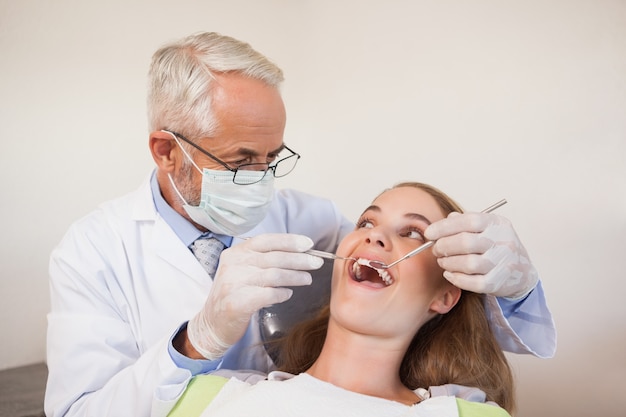 Dentista examinando los dientes de un paciente en la silla de dentistas