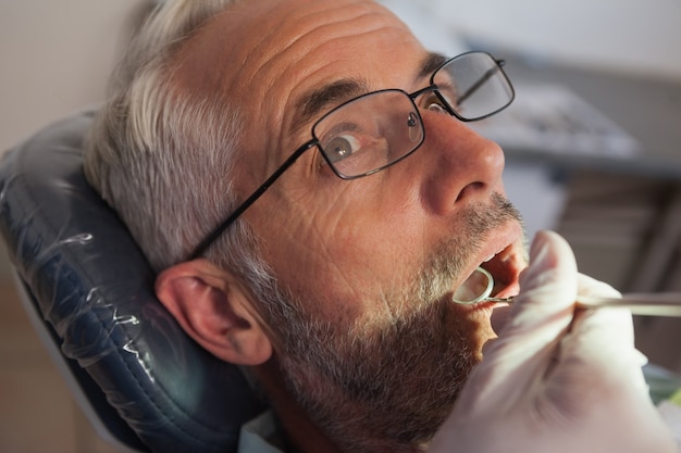 Dentista examinando los dientes de un paciente en la silla de los dentistas