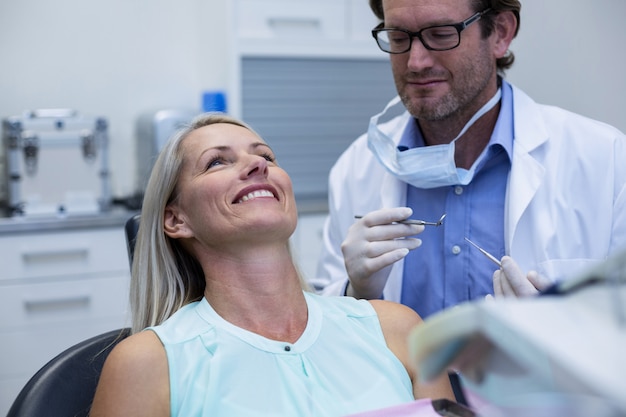 Dentista examinando a una mujer con herramientas