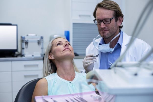 Dentista examinando a una mujer con herramientas