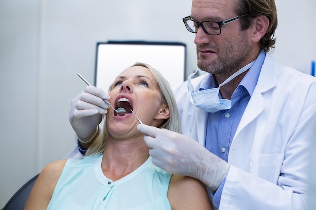 Dentista examinando a una mujer con herramientas