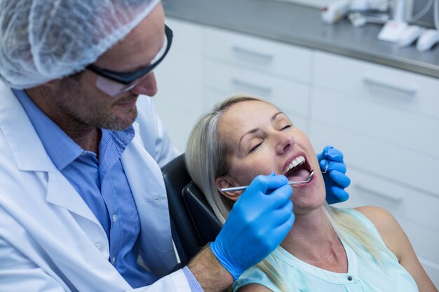 Dentista examinando a una mujer con herramientas