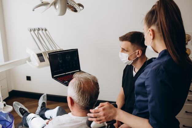 Dentista examinando o raio X dental do idoso