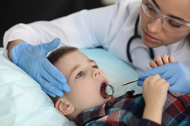 Dentista examinando os dentes da criança com ferramentas de metal