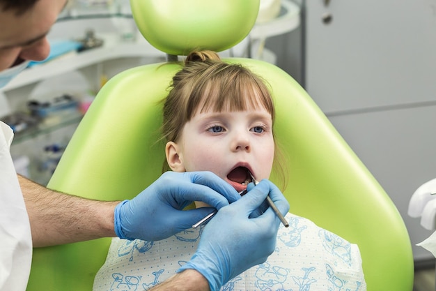 Dentista examinando os dentes da menina na clínica Problema dentário