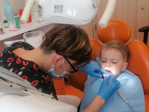 Foto dentista examinando os dentes de um menino na clínica