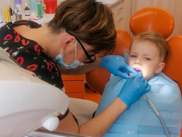 Foto dentista examinando os dentes de um menino na clínica