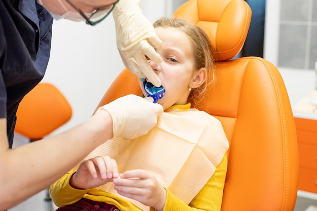 Dentista examinando os dentes de um paciente usando colher de impressão de equipamento odontológico no consultório odontológicoCriança durante a visita do ortodontista e check-up da cavidade oralEstomatologia e cuidados de saúde