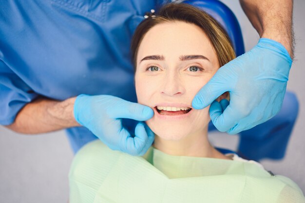 Dentista examinando os dentes de um paciente usando equipamentos odontológicos no consultório odontológico