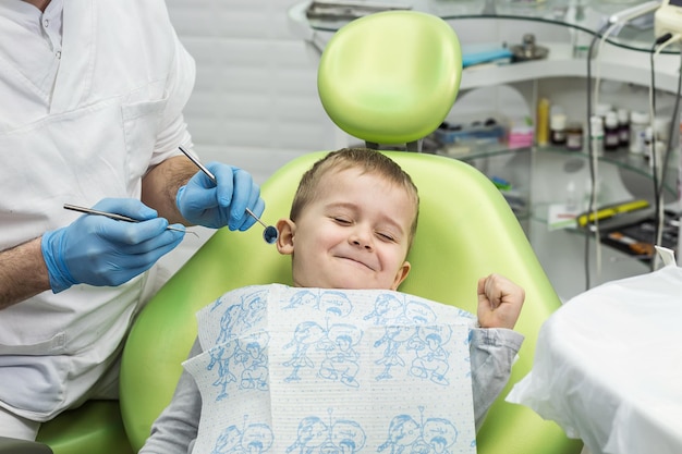 Dentista examinando os dentes do menino na clínica Problema dentário