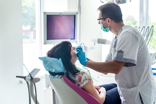 Dentista examinando os dentes do paciente com câmera intraoral