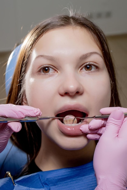 Foto dentista examinando os dentes do paciente com um espelho bucal e escavadeira dental. close-up vista na mulher.