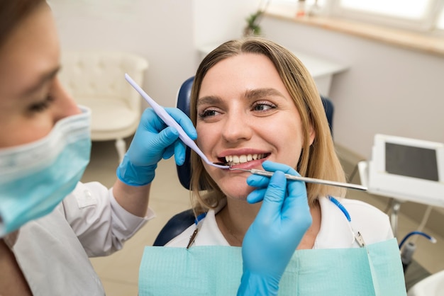 Foto dentista examinando os dentes do paciente no consultório odontológico