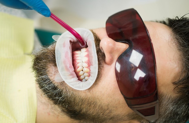Dentista examinando os dentes dos pacientes na clínica de branqueamento dentário
