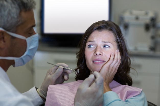 Dentista examinando a una paciente con herramientas