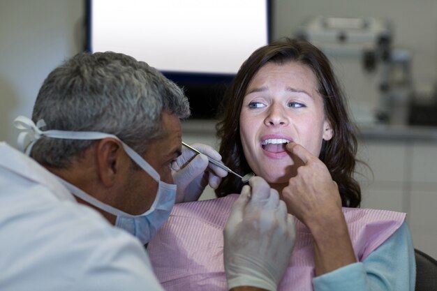 Foto dentista examinando a una paciente con herramientas