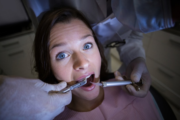 Dentista examinando a una paciente con herramientas