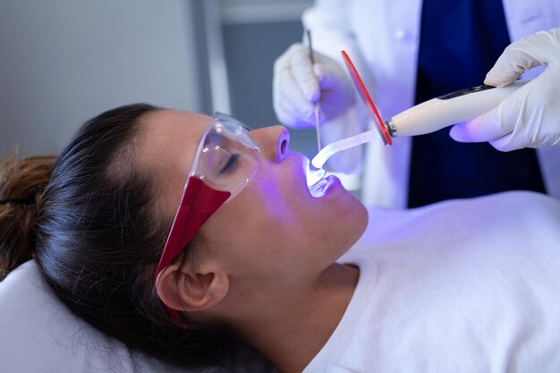 Dentista examinando a un paciente con luz de curación dental en la clínica