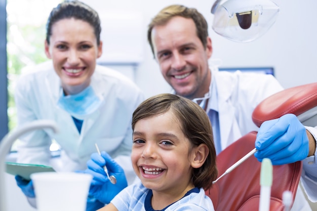 Dentista examinando um jovem paciente com ferramentas em clínica odontológica