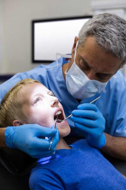 Dentista examinando um jovem paciente com ferramentas