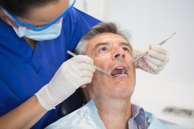 Dentista examinando um paciente com ferramentas