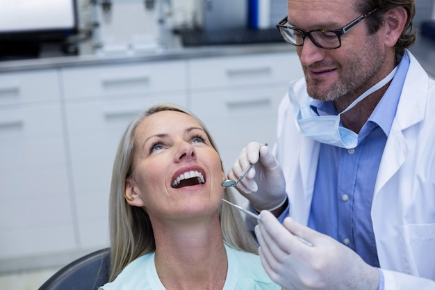 Dentista examinando uma mulher com ferramentas