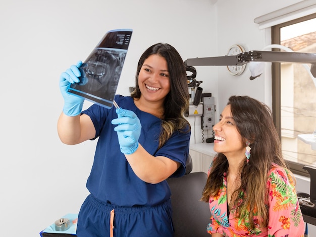 Un dentista experimentado sonríe a su paciente en la oficina mientras muestra una radiografía panorámica