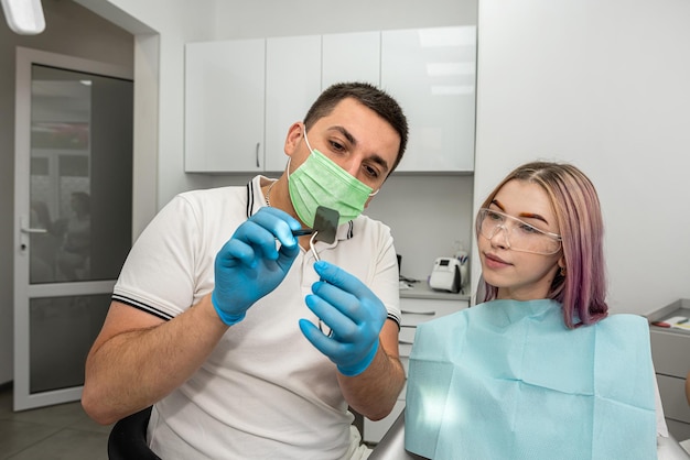 El dentista explica los detalles de una radiografía a su concepto de paciente femenino de consulta en odontología