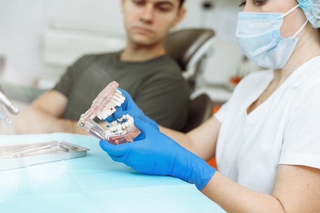Foto dentista explicando com dentes artificiais ao paciente