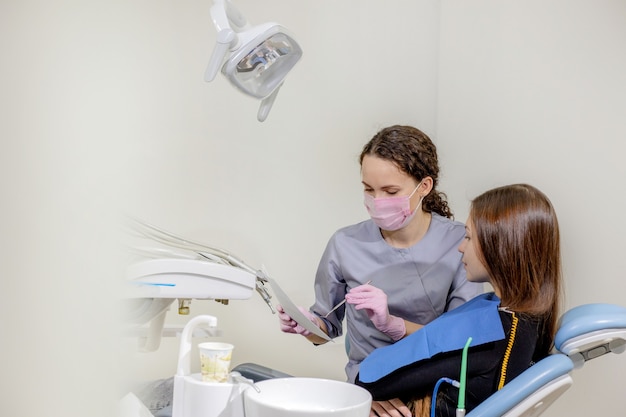 Dentista explicando os detalhes de uma foto de raio-x de dentes para seu paciente na clínica.