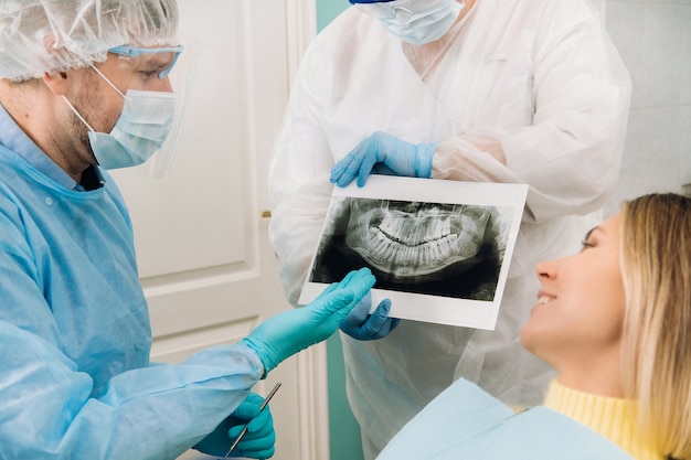 Dentista explicando os detalhes do raio-X para seu paciente no consultório.