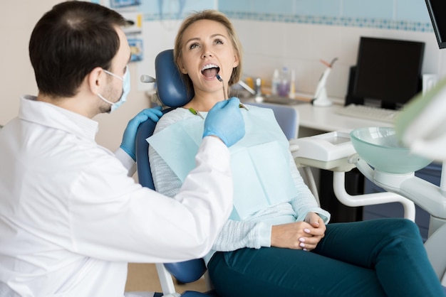 Foto dentista explorando os dentes do cliente