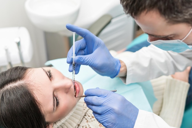 Dentista faz uma injeção anestésica para o paciente