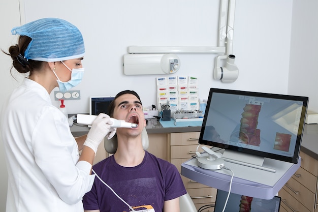 Dentista fazendo escaneamento 3D dos dentes de um cliente