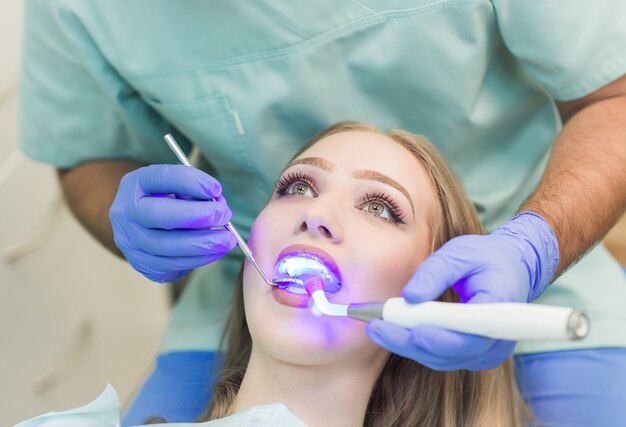 Dentista fazendo procedimento com luz UV de cura dental na clínica