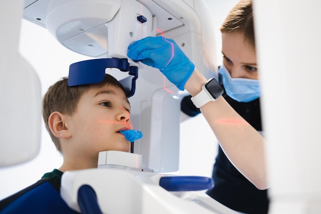 Dentista fazendo radiografia panorâmica dos dentes para um garotinho usando máquina moderna de raio-x