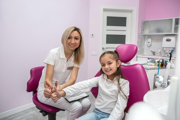 Una dentista feliz está entrevistando a una paciente pequeña en el consultorio de una clínica dental para niños Tecnología de tecnología dental y concepto de atención médica odontología infantil