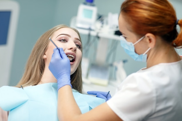 Dentista femenino que controla los dientes pacientes de la muchacha