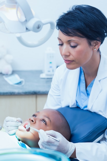 Dentista femenino que examina los dientes de los muchachos