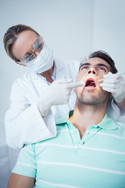 El dentista femenino que examina sirve los dientes