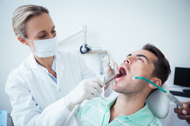 El dentista femenino que examina sirve los dientes